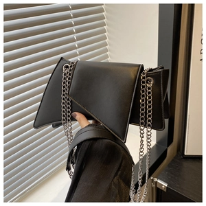 Detail view of black geometric leather bag with silver metal chain straps