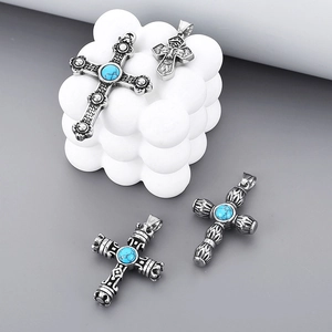 Close-up of vintage titanium steel cross pendants with turquoise and relief details