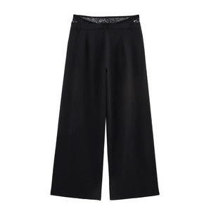Detail view of black high-waisted wide leg trousers with lace patchwork on the waistline