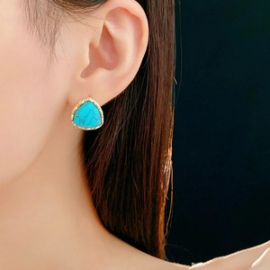 Close-up of vintage geometric turquoise earring with gold metallic trim on a model