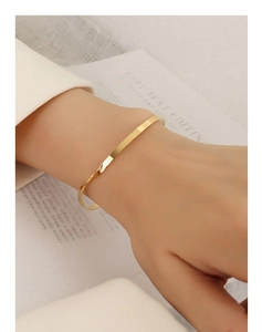 Detail shot of a minimalist gold twisted bangle on wrist with elegant metallic finish