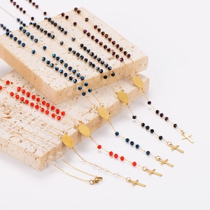 Colliers chapelet dorés avec perles colorées et pendentifs croix sur pierre beige