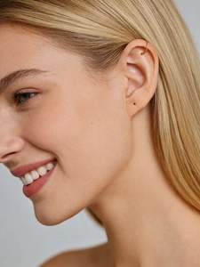 Detailed close-up of a minimalist gold C-shaped ear cuff worn on the upper ear cartilage