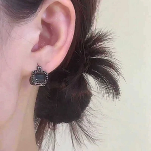 Nahaufnahme eines quadratischen Vintage-Ohrrings mit schwarzem Edelstein am Ohr.