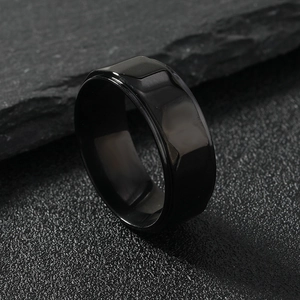 Minimalist 8mm black geometric faceted stainless steel ring on dark textured stone