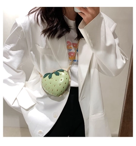 Close-up of light green strawberry-shaped bag with gold rivets and chain strap