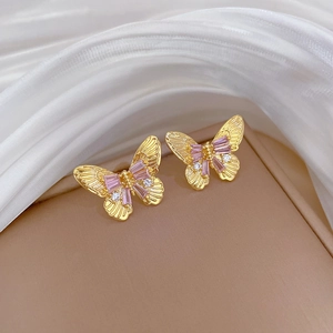 Macro view of gold bow earrings featuring pink rectangular gemstones and small diamonds