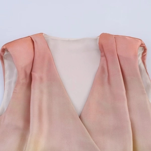 Détail du col en V sur un haut sans manches dégradé rose et jaune en satin