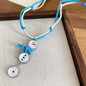 Vue détaillée du collier pendentif bonhomme de neige avec gland bleu et cordon tressé