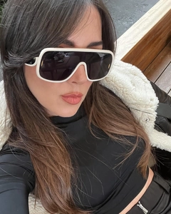 Fashionable oversized white sunglasses with black lenses worn by a model on a bench