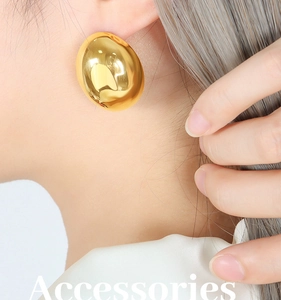 Detailed close-up of chunky gold bean earrings with a mirror-polished metallic finish
