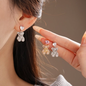 Détail de boucles d'oreilles ours en zircon avec clous en cœur plaqués or et argent