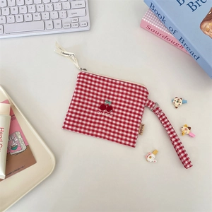 Close-up of a red checkered coin pouch with cherry embroidery on a desktop background