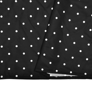 Gros plan sur le tissu noir à pois blancs de la robe rétro montrant les détails de l'ourlet