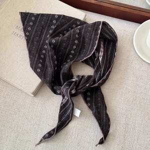 Close-up of vintage floral striped cotton bandanna scarf laid on a neutral textured fabric