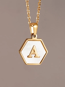 Vista macro de un colgante hexagonal de oro de 18K con nácar blanco y la letra A
