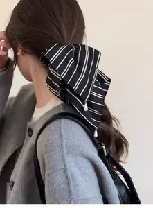 Détail d'un chouchou ruban rayé avec perle porté sur une queue de cheval basse