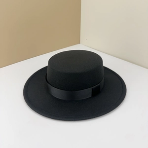 Detail of black wool boater hat featuring a sleek grosgrain ribbon band and fine texture