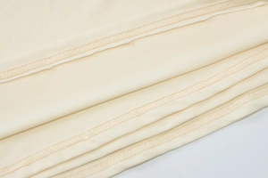 Detailed close-up of beige knitted fabric with high-quality stitching and soft texture