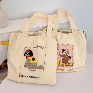 Detail of cream canvas tote bags featuring delicate dog and cat embroidery patterns