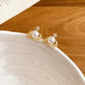 Macro shot of gold crown stud earrings with a white pearl and zircon accents