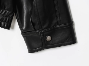 Détail du poignet d'une veste en cuir noir avec boutons-pression en métal et coutures