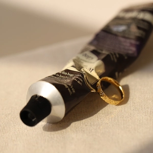 Close-up of golden ring with hammered dragon scale texture on skincare tube