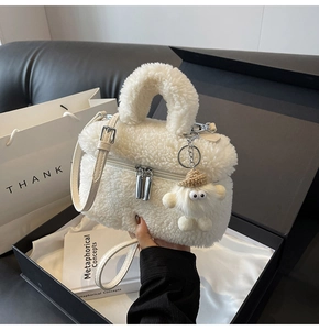 Detailed view of white faux shearling handbag with silver hardware and plush charm accessory