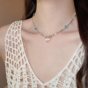 Detailed view of the clear heart pendant on a beaded necklace worn by a fashion model