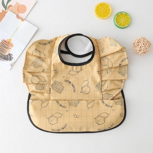 Close-up of waterproof beige baby bib with plaid pattern and cute pancake prints