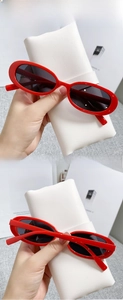 Detail of red cat-eye sunglasses with grey lenses and a stylish vintage Y2K aesthetic