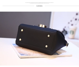 Detail view of black lychee grain handbag base with protective gold metal feet and hardware