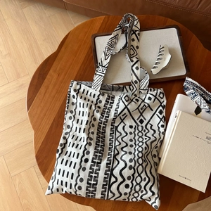 Détail d'un sac cabas en lin bohème avec motifs géométriques noirs sur table en bois