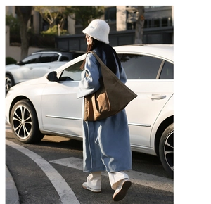 Chic brown tote bag carried by a model in a blue coat and white faux fur hat