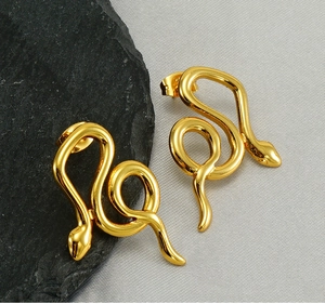 Detailed close-up of golden snake-shaped earrings on a black stone and grey background