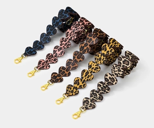 Detailed view of five leopard print bag straps with scalloped edges and gold metal buckles
