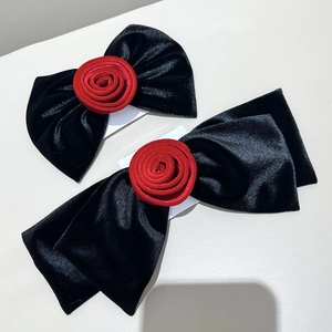 Détails d'élégantes barrettes en velours noir ornées de roses rouges en tissu doux