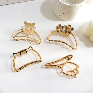 Golden metal hair claw clips set featuring panda, floral and cat ear shapes on a white table