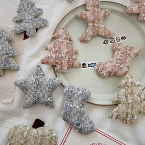Macro shot of tweed Christmas tree and star ornaments in soft pink and grey tones