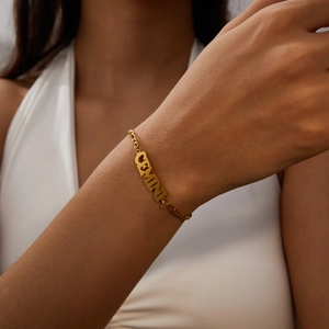 Close-up of gold Gemini zodiac pendant bracelet on a woman's wrist with a luxury finish