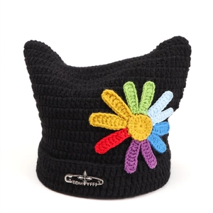 Detail of black cat ear knit beanie with colorful crochet flower and silver pin