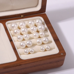 Detail view of various sizes of pearl studs displayed in a premium wooden jewelry box