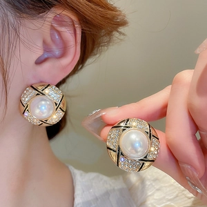 Detail of vintage gold button earrings with white pearl and rhinestone accents
