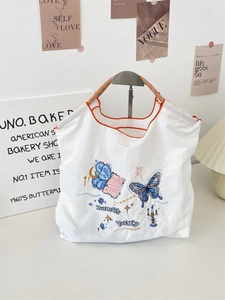 Detail of embroidered canvas tote bag with orange piping and vintage butterfly print