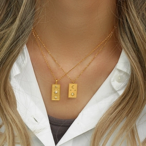 Close-up of layered gold necklaces with moon star pendants and cubic zirconia accents