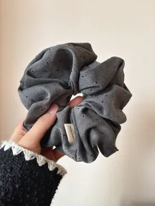 Detail of dark grey handmade scrunchie with bead embellishments and fabric label