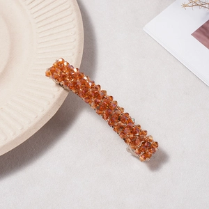 Gros plan d'une pince à cheveux en perles de cristal orange sur plat en céramique