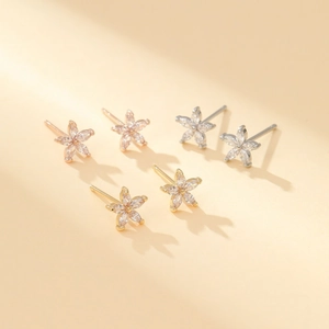 Detailed view of flower-shaped stud earrings in gold, silver, and rose gold with marquise zircons