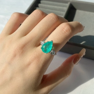 Macro shot of 925 silver ring featuring a pear-cut Paraiba gemstone with emerald zircons