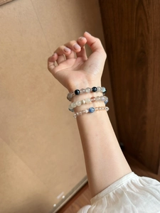 Detailansicht von drei verschiedenen Kristallperlenarmbändern an einem weiblichen Handgelenk